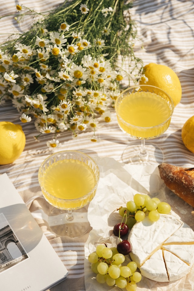 Eine Picknickdecke mit Zitronenlimo, Blumen, Trauben und Käse