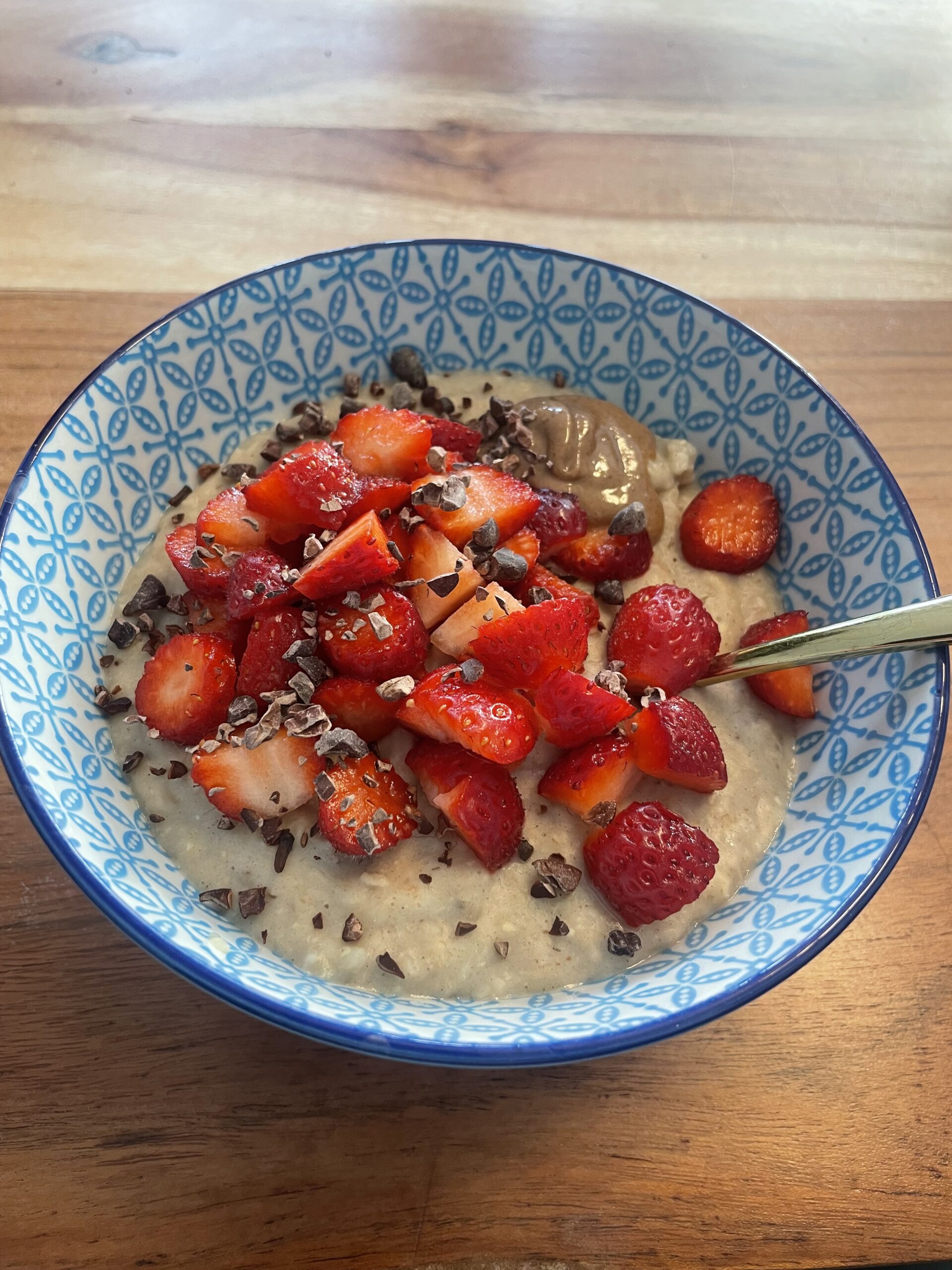Eine Schüssel mit Porridge, Erdbeeren, Kakaonibs und Nussmus